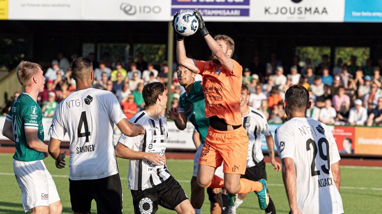 Målvakten greppar bollen framför många spelare.