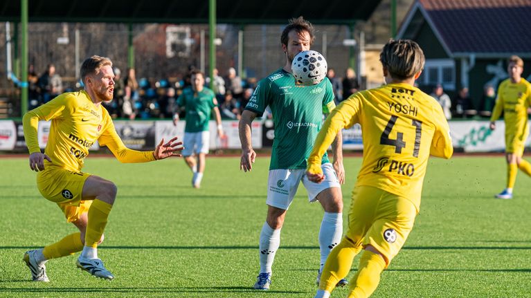 En spelare i grön spelskjorta tar ned bollen med bröstet.