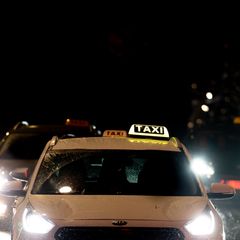 Taxis driving at night, with the lights on.