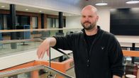 Huppariin pukeutunut kalju ja parrakas mies nojaa metalliseen sisäkaiteeseen.