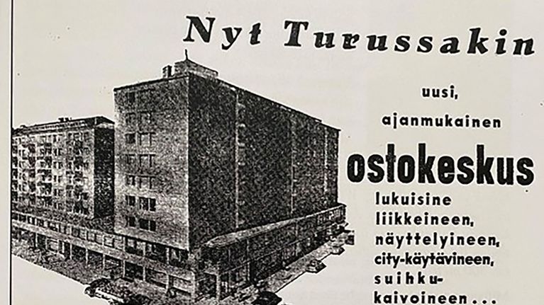 Svartvit annons med foto av ett flerbostadshus, texten beskriver det nya köpcentret Puutorinkulma i Åbo.