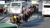 Ihmiset jonottavat paikallisliikenteen bussiin.
