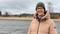En kvinna som ler, i bakgrunden en grusplan. 