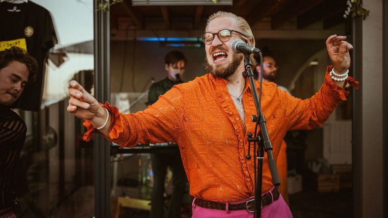 Musikern och sångaren Gustav Nyström uppträder i orange skjorta och rosa byxor.