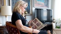 Soili Karme katsoo kädessään olevaa valokuva-albumia.
