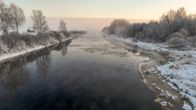 Talvinen jokimaisema. Ohuita jäälauttoja virtaa joessa ja usvaa nousee joesta.