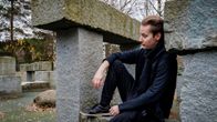 Ville Leppänen istuu syksyisessä parkour-puistossa harmaiden kivipaasien välissä.