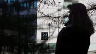 En suddig silhuett av en person står framför en byggnad.