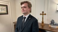 Puolalainen nuori Bartosz Florek seisoo pöydän edessä, jossa ovat Jeesus ristillä -veistos ja leijona-patsas.