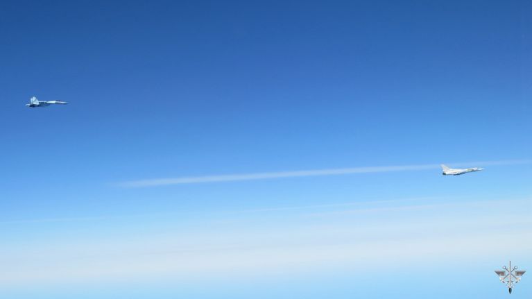 Two military jets flying in a blue sky.