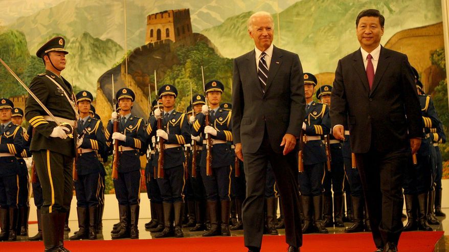 Varapresidentit Biden ja Xi kävelevät punaisella matolla, taustalla kiinalainen kunniavartiosto ja vuoristomaisemaa esittävä maisema. 