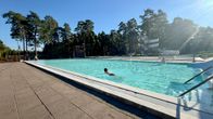 Aurinkoinen päivä ulkouimalassa, jossa uimarit nauttivat kirkkaasta vedestä.