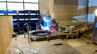 Hitsaaja työskentelee metalliverstaassa, ympärillään erilaisia työkaluja ja välineitä.