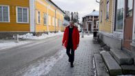 Mies kävelee jalkakäytävällä punainen takki auki.