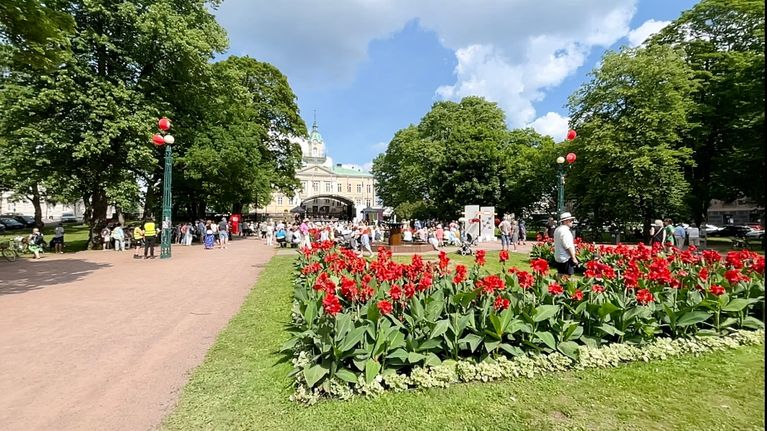 Suomi areena keskustelu Porin Raatihuoneenpuistossa, punaisset kukkaistutukset etualalla.