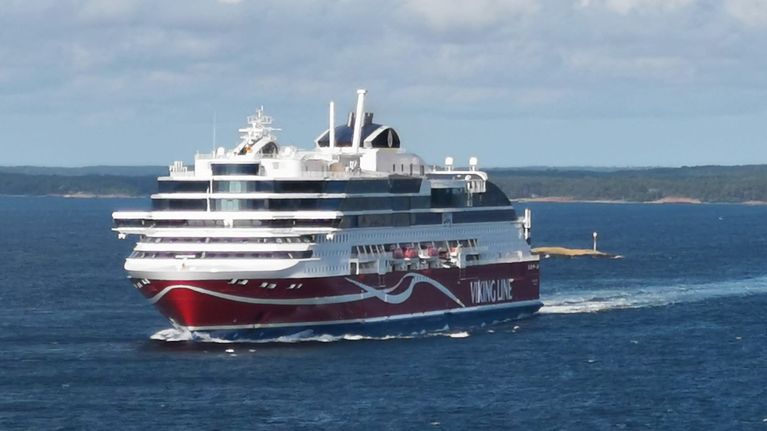 Viking Lines fartyg färdas på öppet vatten med mindre öar och kustlinje i bakgrunden.
