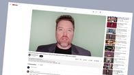Kuvakaappaus Youtubesta, jossa näkyy harmaaseen pukeutunut mies puhumassa kameralle.