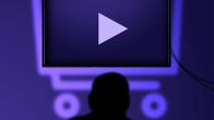 Kuvitettu hahmo katsoo televisioruutua. Taulutelevision takana hohtaa ostoskärryn muotoinen valo.