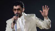 Artisten Bad Bunny iklädd vit kostym sjunger i en mikrofon.