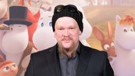 Ville Haapasalo Muumilaakso-sarjan ensi-iltatilaisuudessa takanaan Muumilaakso-juliste.