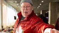 Pipopäinen vanhempi mies ottamassa leipäpussia SPR:n ruokajaossa.