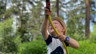 Kolmevuotias Urho Tuominen suihkuttaa vettä letkulla kahluualtaan vieressä.