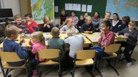 Salapoliisikerholaisia pöydän ääressä luokassa.