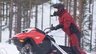 Mies ajaa moottorikelkalla metsässä.