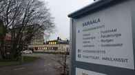 Oulaskankaan sairaalan opastekyltti, jonka takana näkyy sairaala.