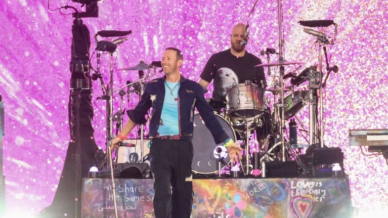 Coldplayn laulaja seisoo rumpujen edessä lavalla.