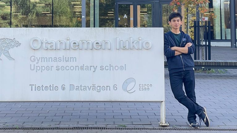 Nuori mies nimeltä Faru Yusupov nojaa kyltiin jossa lukee "Otaniemen lukio"