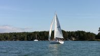 En segelbåt med vita segel seglar i medvind.