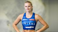 Nainen katsoo kameraan yleisurheiluvaatetuksessa kädet lanteillaan.