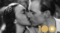 Nainen ja mies (näyttelijät Eila Pehkonen ja Matti Oravisto) suutelevat, kuva elokuvasta Ihmiset suviyössä, kuvassa myös logo "Yle 100 toive-elokuvaa"..