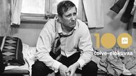 Väsyneen näköinen mies (Mikko Niskanen) istuu kauluspaidan nappi auki ja kravatti sivuun vedettynä sängynreunalla, kuvassa teksti "Yle 100 toive-elokuvaa".