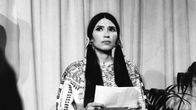 Sacheen Littlefeather pitelee käsissään paperille kirjoitettua puhetta.