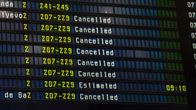 Airport departures board with "Cancelled" repeated after many flight numbers.