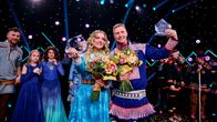 Ellinor Halvari ja Ánte Niillas Bongo lavalla Sámi Grand Prix palkintojen kanssa. Taustalla näkyvät muut kilpailuun osallistuneet.
