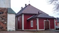Porvoon Pikkukirkko ulkoa, punainen vaakalaudoitus ja valkoiset ikkunanpuitteet ja rakennuksen kulmalaudat.