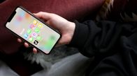 Henkilö makaa sohvalla ja katsoo puhelinta. Puhelimen näytöllä näkyy sosiaalisen media applikaatioita.
