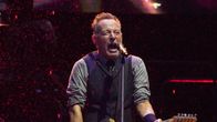 Bruce Springsteen laulaa kitaran kanssa lavalla kaatosateessa.