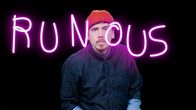 Kuvassa Viikon Tuukka eli toimittaja Tuukka Pasanen katsomassa kameraan ja hänen edessään lukee neonpinkein kirjaimin runous.