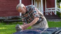 En man i rutig skjorta (Ulf Johansson) putsar stjärnan av en Mercedes.