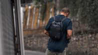 En ung man fotograferad bakifrån. Det ser ut som om han går och tittar ner i sin mobil.