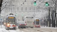 Kuvassa on raitiovaunuja ja autoja sankassa lumisateessa Wienissä.