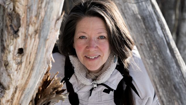 Kaarina Davis puunrunkojen keskellä.