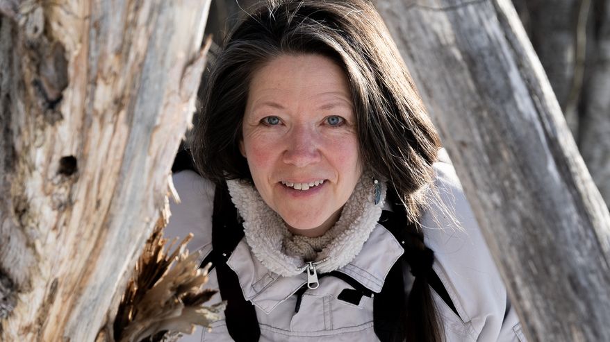 Kaarina Davis puunrunkojen keskellä.