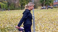Vaaleahiuksinen nainen venyttää etureittä ennen lenkille lähtöä. Maisema on syksyinen.