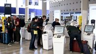 Matkustajat käyttämässä Finnairin itsepalveluautomaatteja lentoasemalla lähtöselvitystä varten.