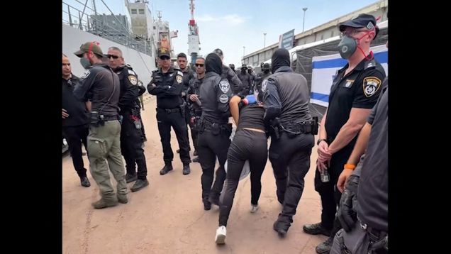 Israeli soldiers forcibly carrying away an activist, with a crowd of authorities standing around.